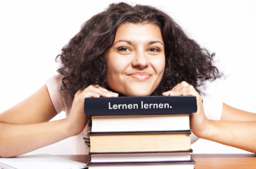 Schülerin balanciert einen Stapel Bücher auf dem Kopf, Aufschrift „lernen lernen“